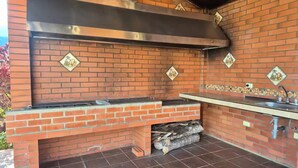 Un espace barbecue extérieur en briques, doté d’une hotte en acier inoxydable et d’un évier.