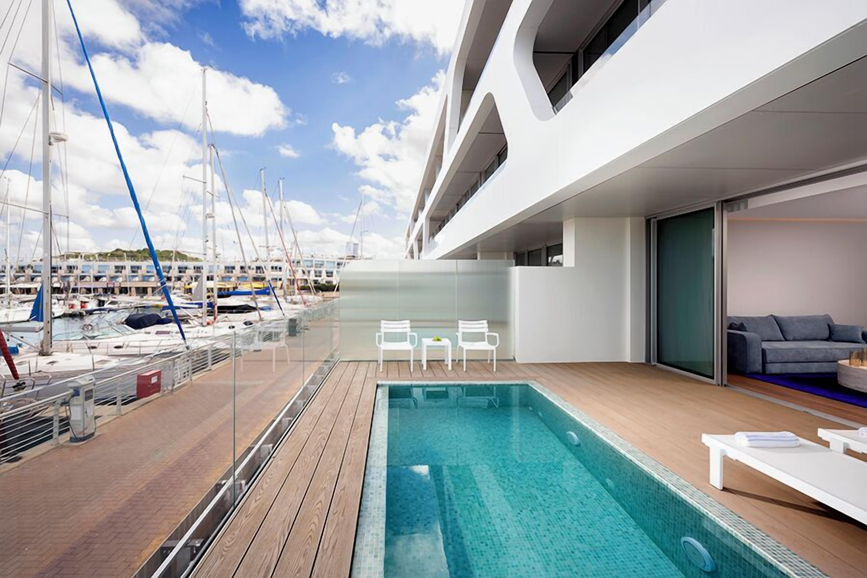 Un área de piscina moderna con vistas a un puerto deportivo, incluyendo barcos y yates.