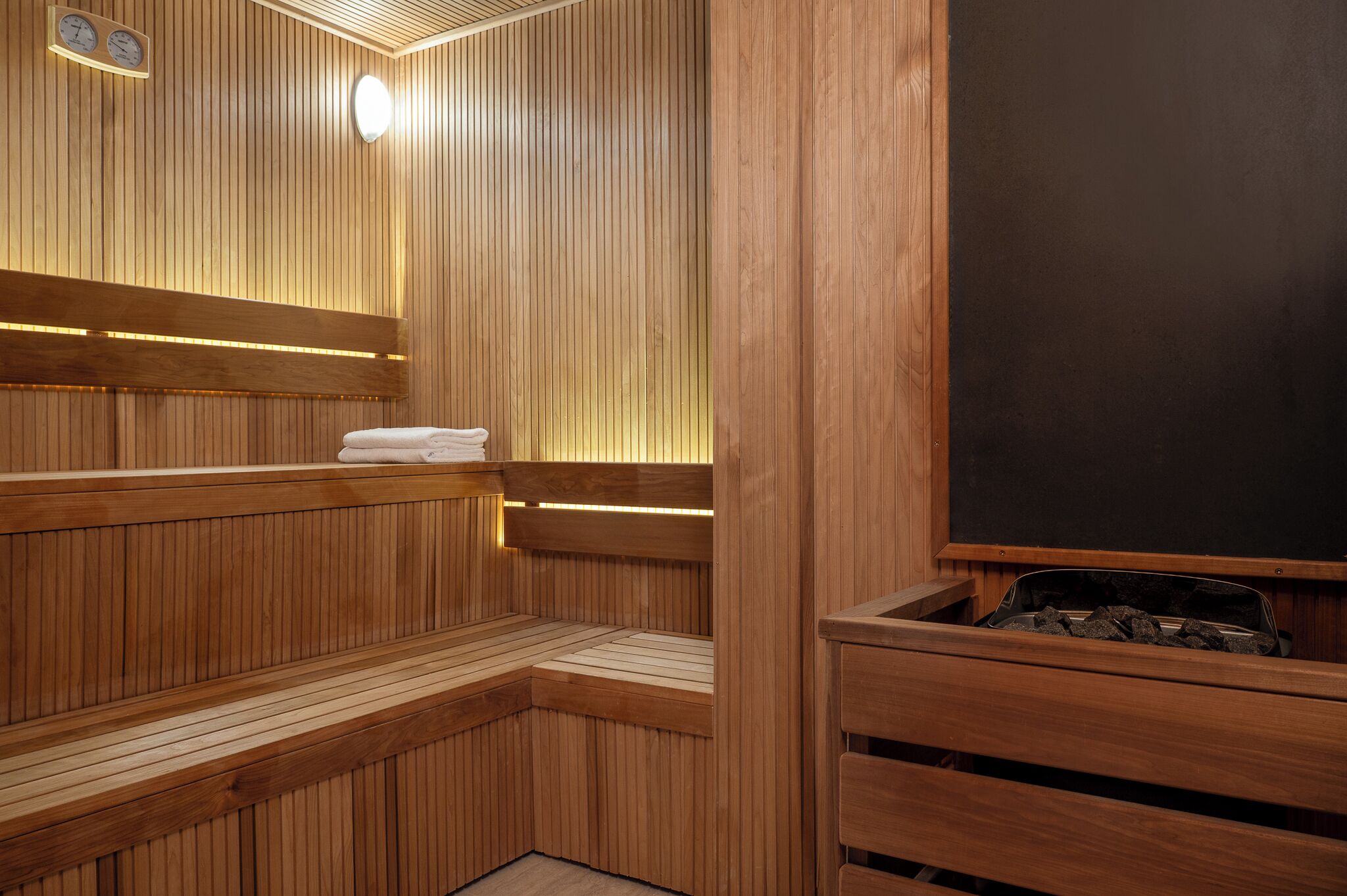 A sauna with wooden benches and a black heating element.