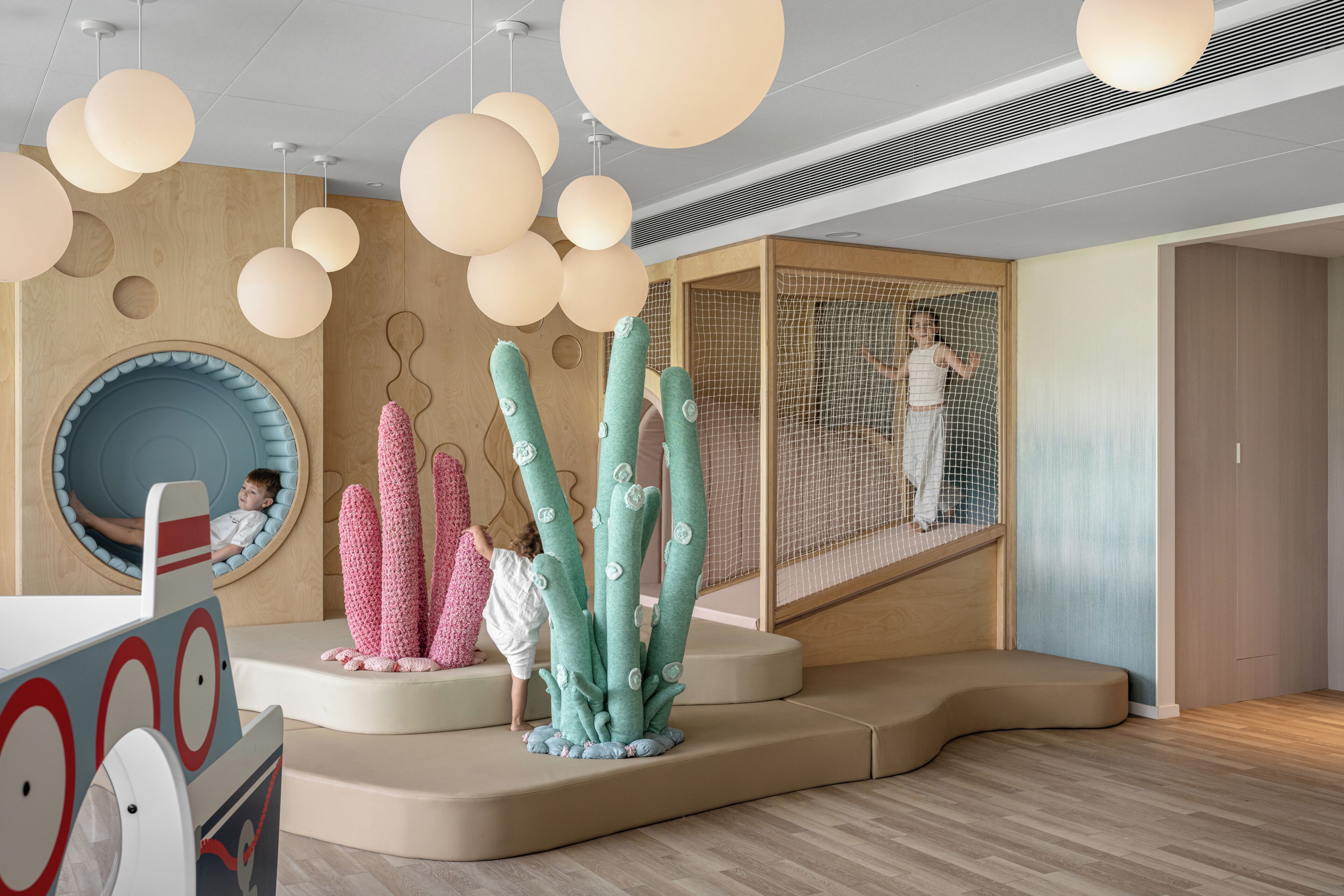 A play area with soft seating, a climbing structure, and a hanging light fixture.