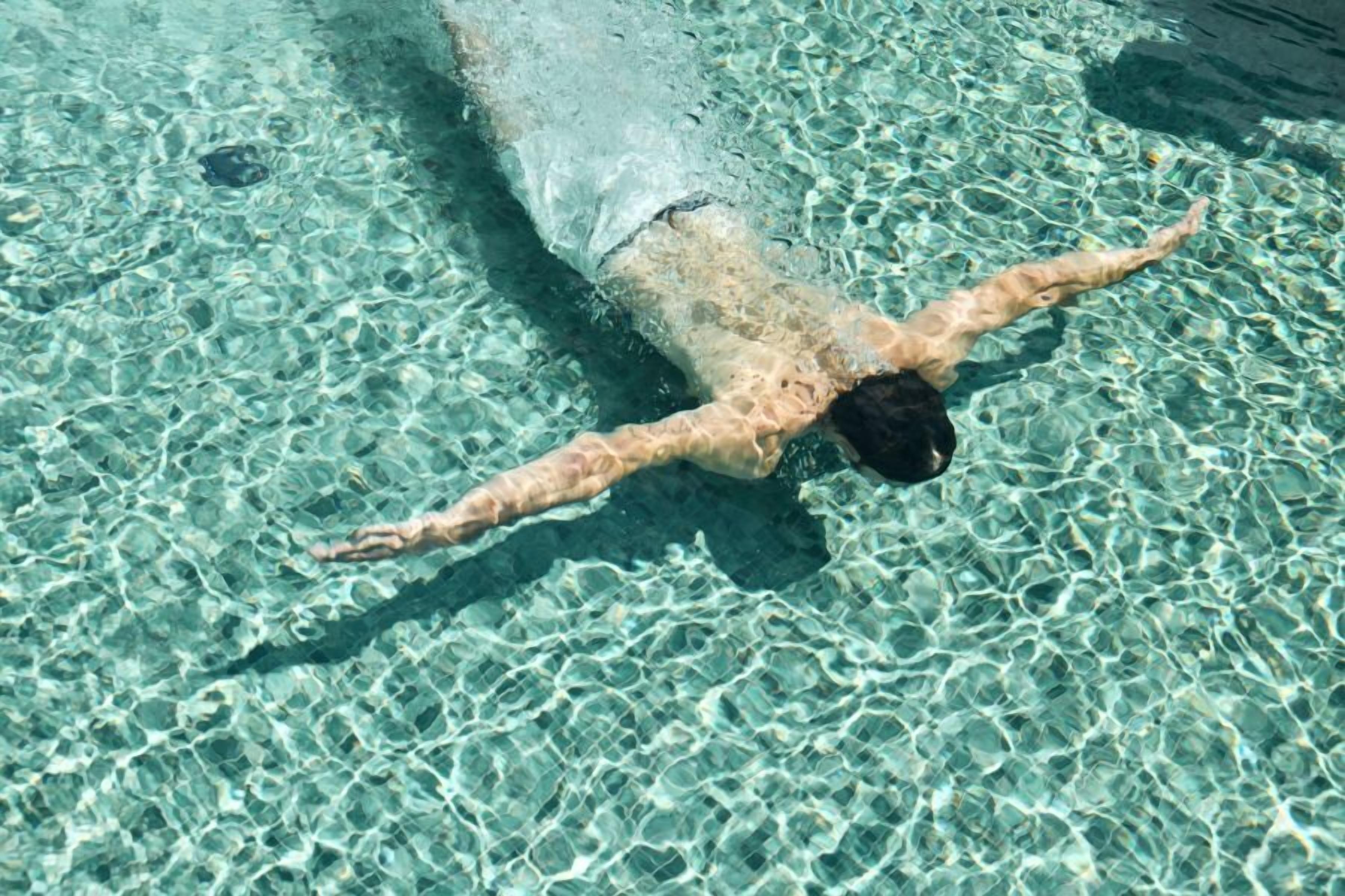 Une piscine aux eaux cristallines dans laquelle nage une personne.