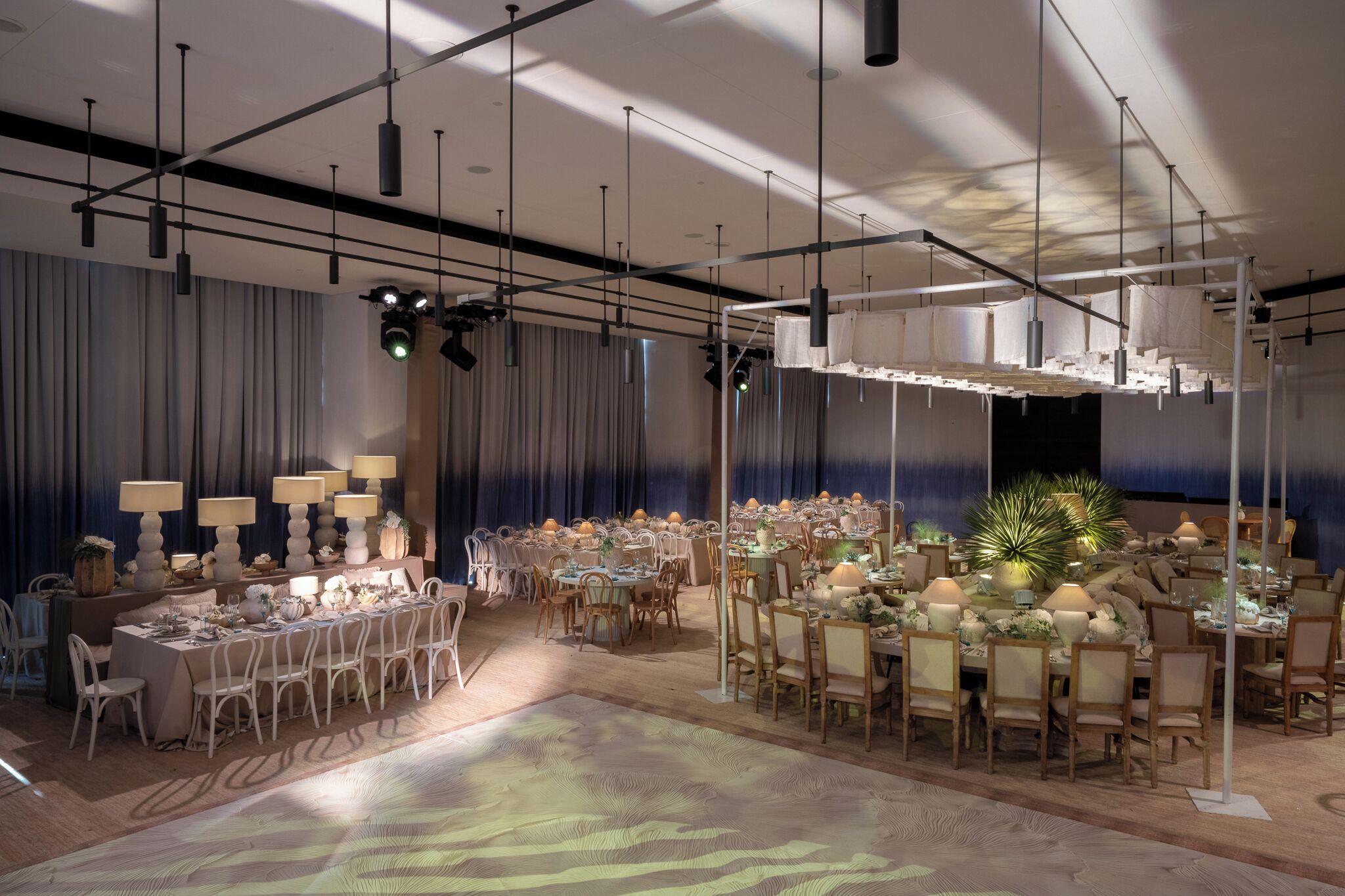 Un amplio salón de banquetes con varias mesas redondas, candelabros y un gran arreglo floral central.