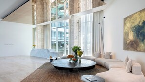 A spacious living area with a round coffee table, a sofa, and a large window providing a view of the outside. - The YACHT – Limited Edition By Fattal (Herzliya)