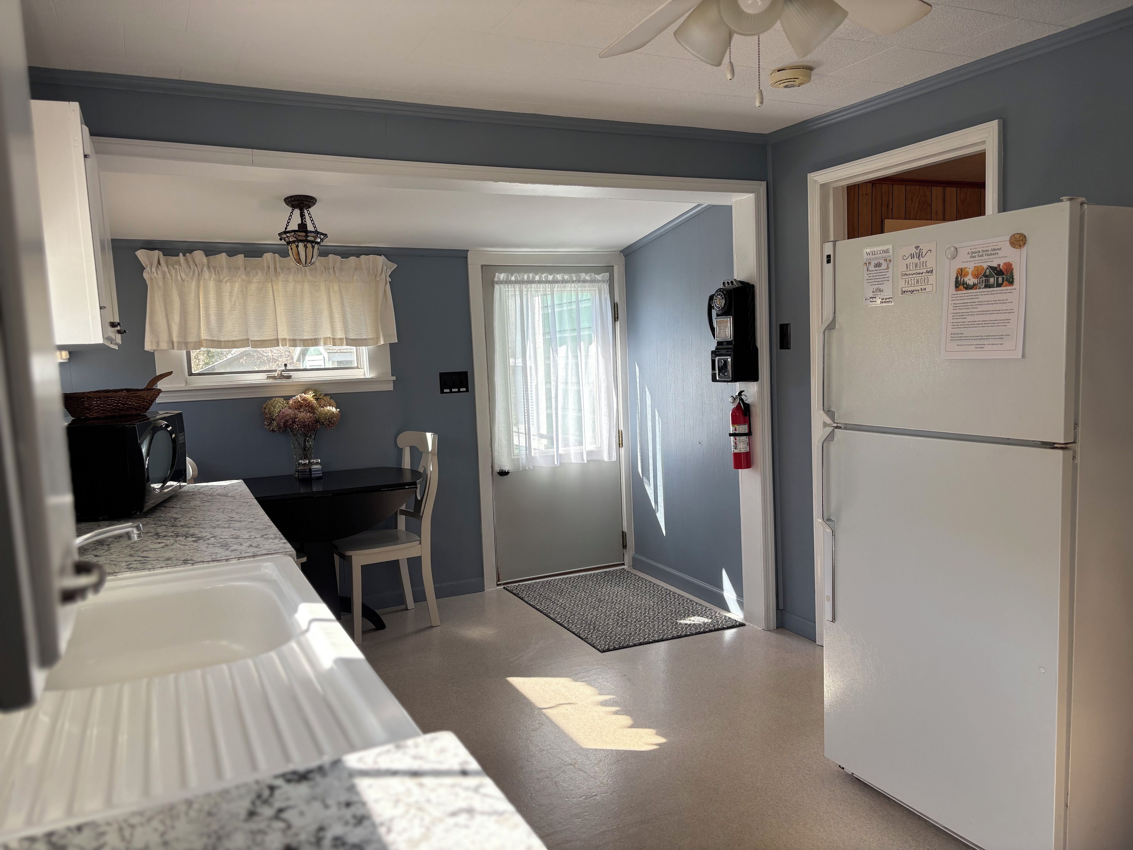 A kitchen with a refrigerator, microwave, and a dining table with chairs.