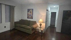 A living room with a sofa, a lamp, and a poster on the wall. - Spacious 6-bedroom apartment with AC in peaceful Detroit (Detroit)