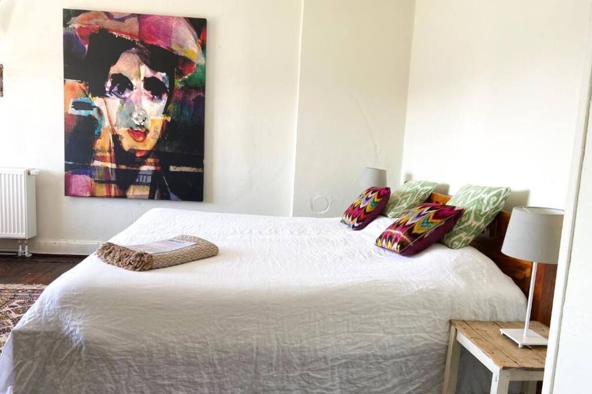 A neatly made bed with a white duvet, colorful pillows, and a small bedside table with a lamp.
