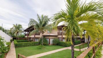 Un resort con edificios de varios pisos, un césped bien cuidado y palmeras.