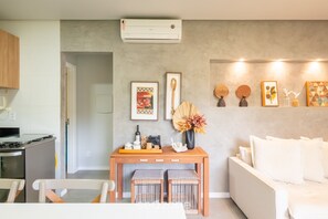 Un salon moderne avec un canapé, une table basse en bois et un climatiseur fixé au mur.