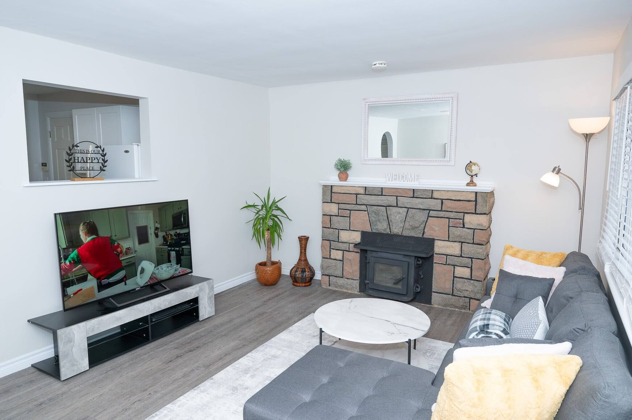 A modern living room with a flat-screen TV, a stone fireplace, a sofa, and a coffee table.