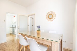 Un espace repas moderne avec une table à plateau en verre, des chaises blanches et un élément décoratif mural.
