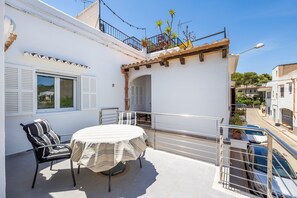 En balkon med et bord, stole og gelænder, samt udsigt til gaden.