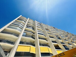Ein Hochhaus mit mehreren Balkonen und blauem Himmel.