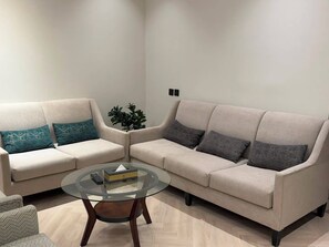 A living room with two sofas, a glass coffee table, and a potted plant. - Thawari Hotel Apartments (Riyadh)
