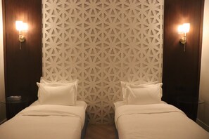 A hotel room with two beds, a geometric patterned wall, and two bedside lamps. - Thawari Hotel Apartments (Riyadh)