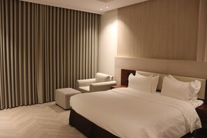 A hotel room with a large bed, a nightstand, a chair, and a wall-mounted TV. - Thawari Hotel Apartments (Riyadh)