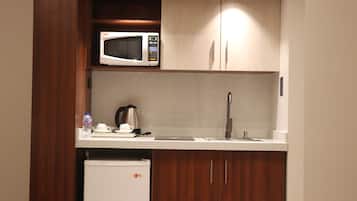 Una kitchenette compacta con microondas, cafetera y un refrigerador pequeño.