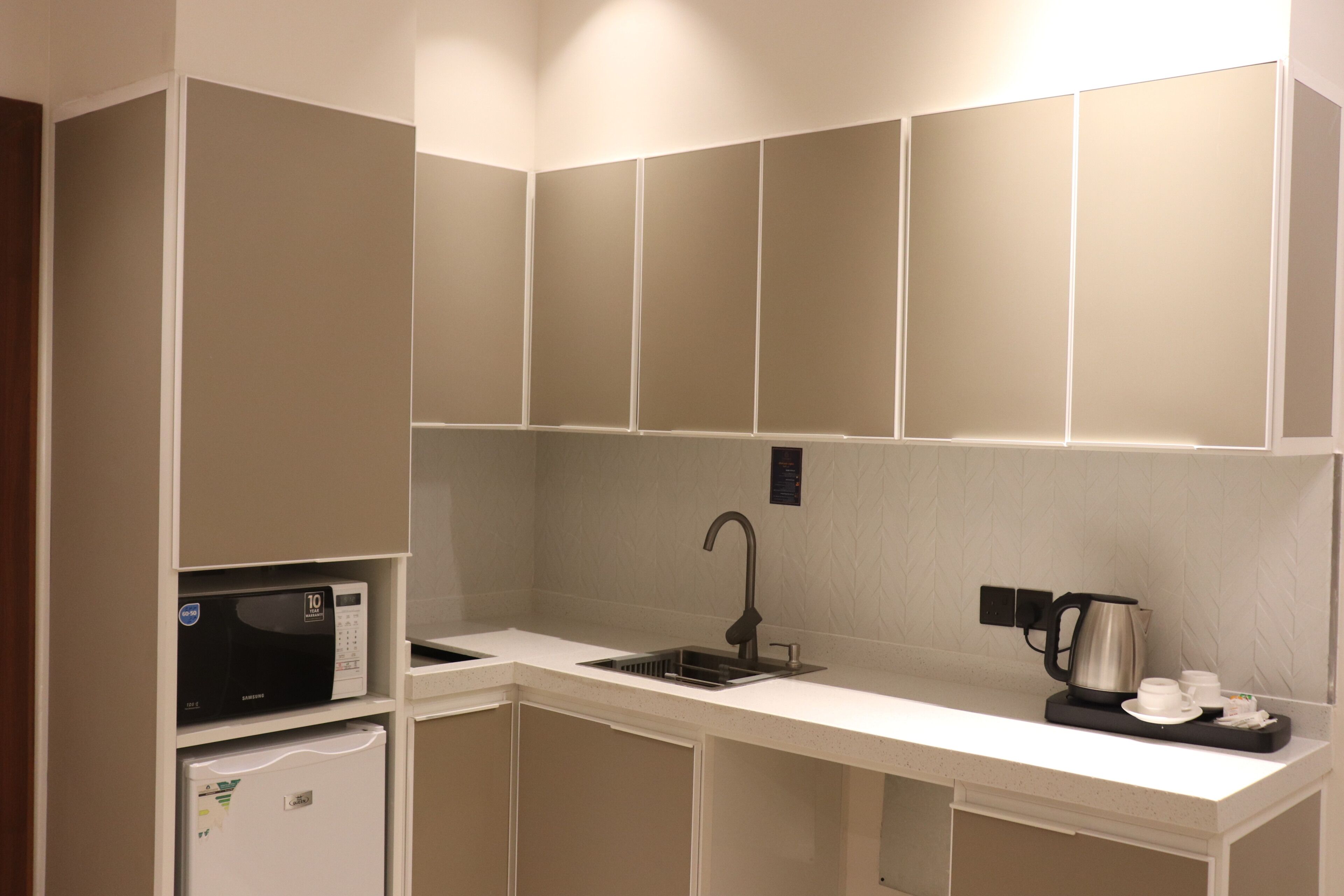 Una kitchenette compacta equipada con microondas, hervidor y pileta.