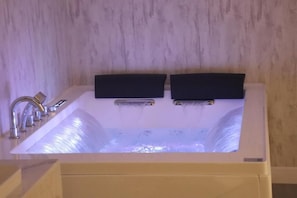 Un baño moderno con bañera integrada, un solo grifo y panel de control en la pared.