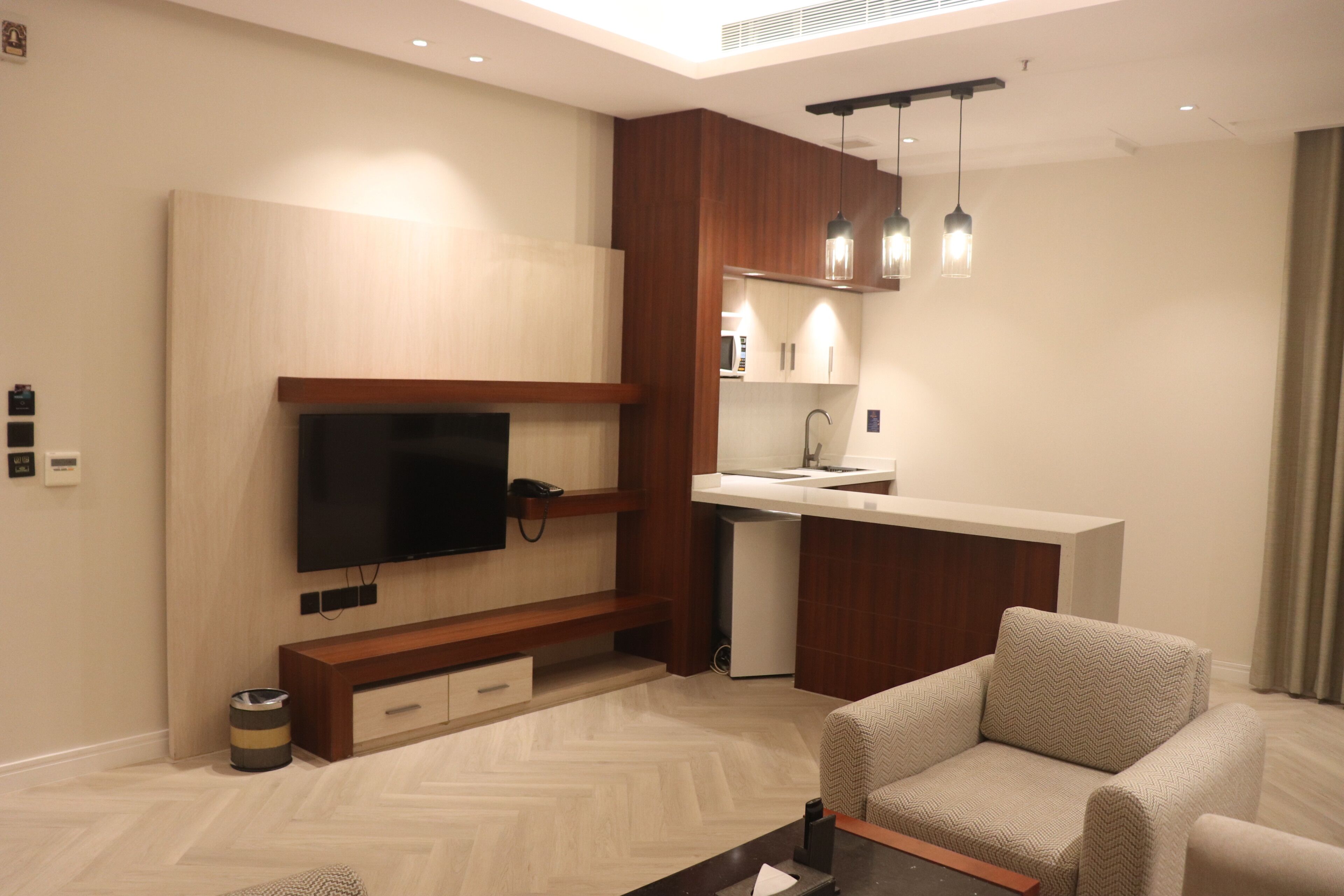 Una sala de estar moderna con un televisor de pantalla plana, mueble de madera para entretenimiento y un sofá.
