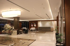 A modern lobby with a reception desk, seating area, and a large chandelier. - Thawari Hotel Apartments (Riyadh)