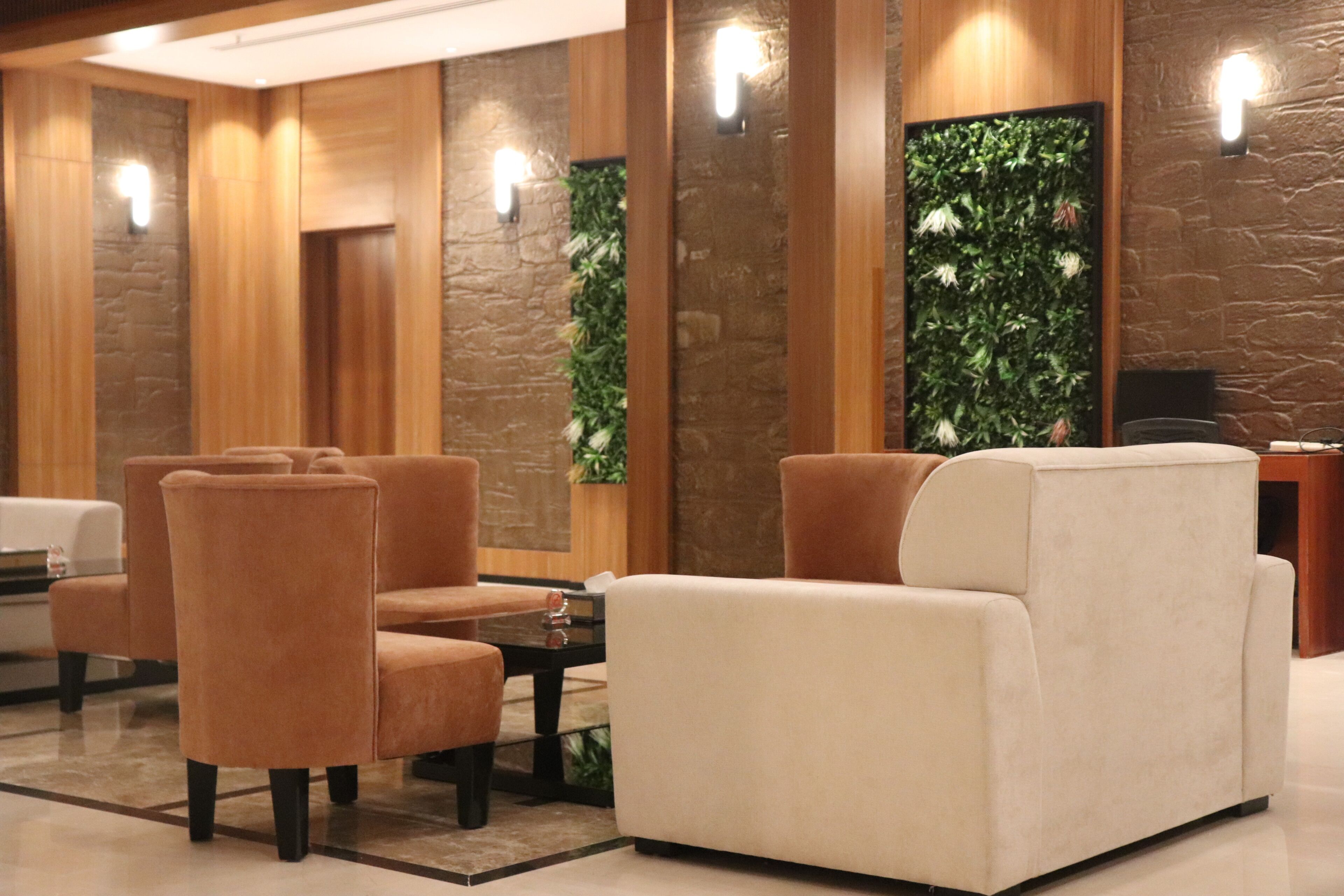 A lobby with seating, a reception desk, and a wall with a green plant.