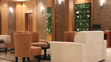 Vestíbulo con asientos, una recepción y una pared con planta verde.