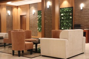 A lobby with seating, a reception desk, and a wall with a green plant. - Thawari Hotel Apartments (Riyadh)