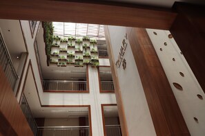 Een meerlaags interieur met een centraal atrium, voorzien van een verticale tuin, houten lambrisering en een bordje dat een hotel aangeeft.