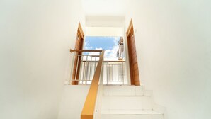 A staircase with a handrail leading to a window with a view of the sky. - Griya Asy-Syifa Homestay by ARBA (Yogyakarta)