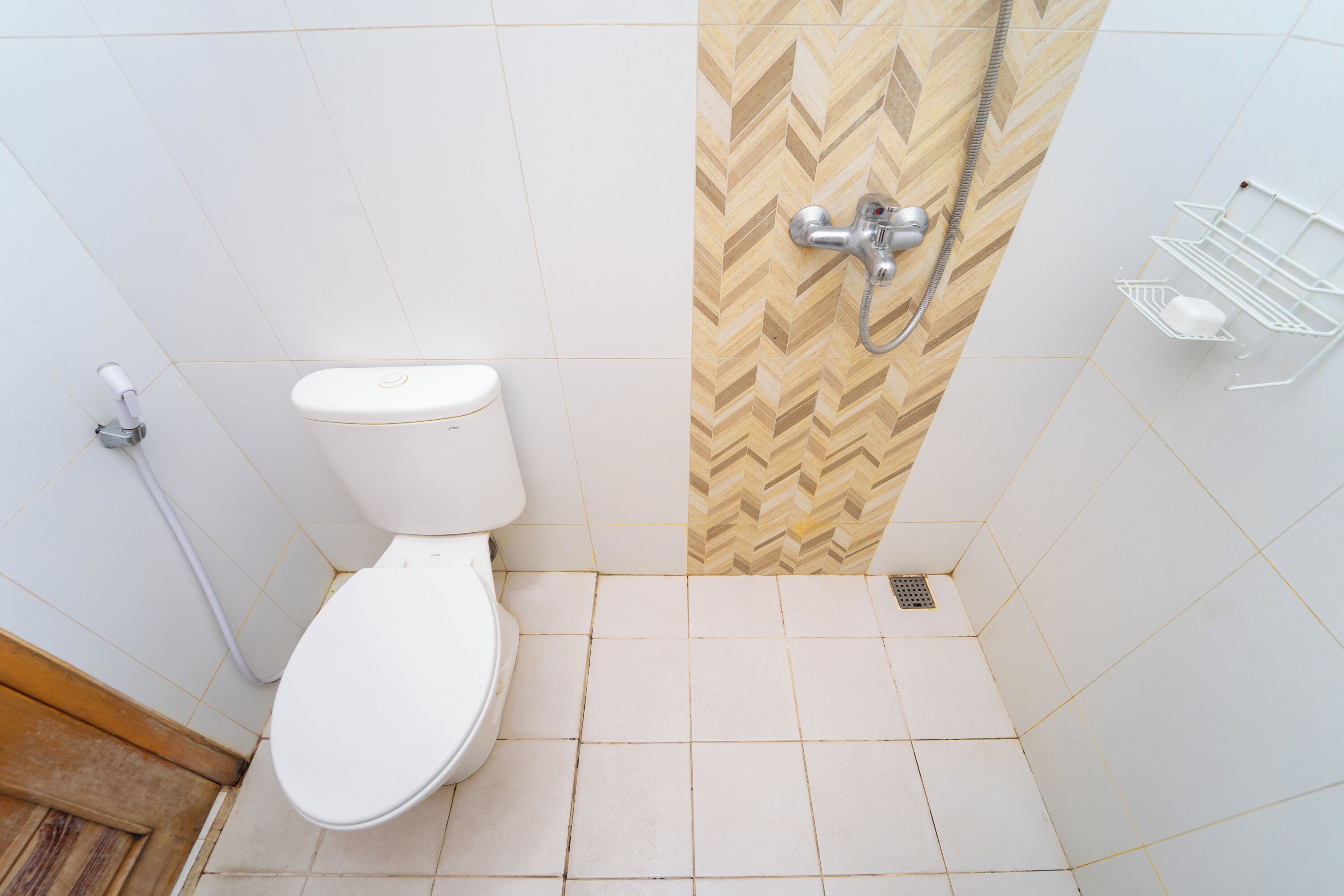 A bathroom with a toilet, shower, and a white tiled floor.