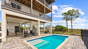 A two-story house with a swimming pool, outdoor seating, and a fenced yard. - Pet Friendly Beach House - Seminole Wind (Port St. Joe)