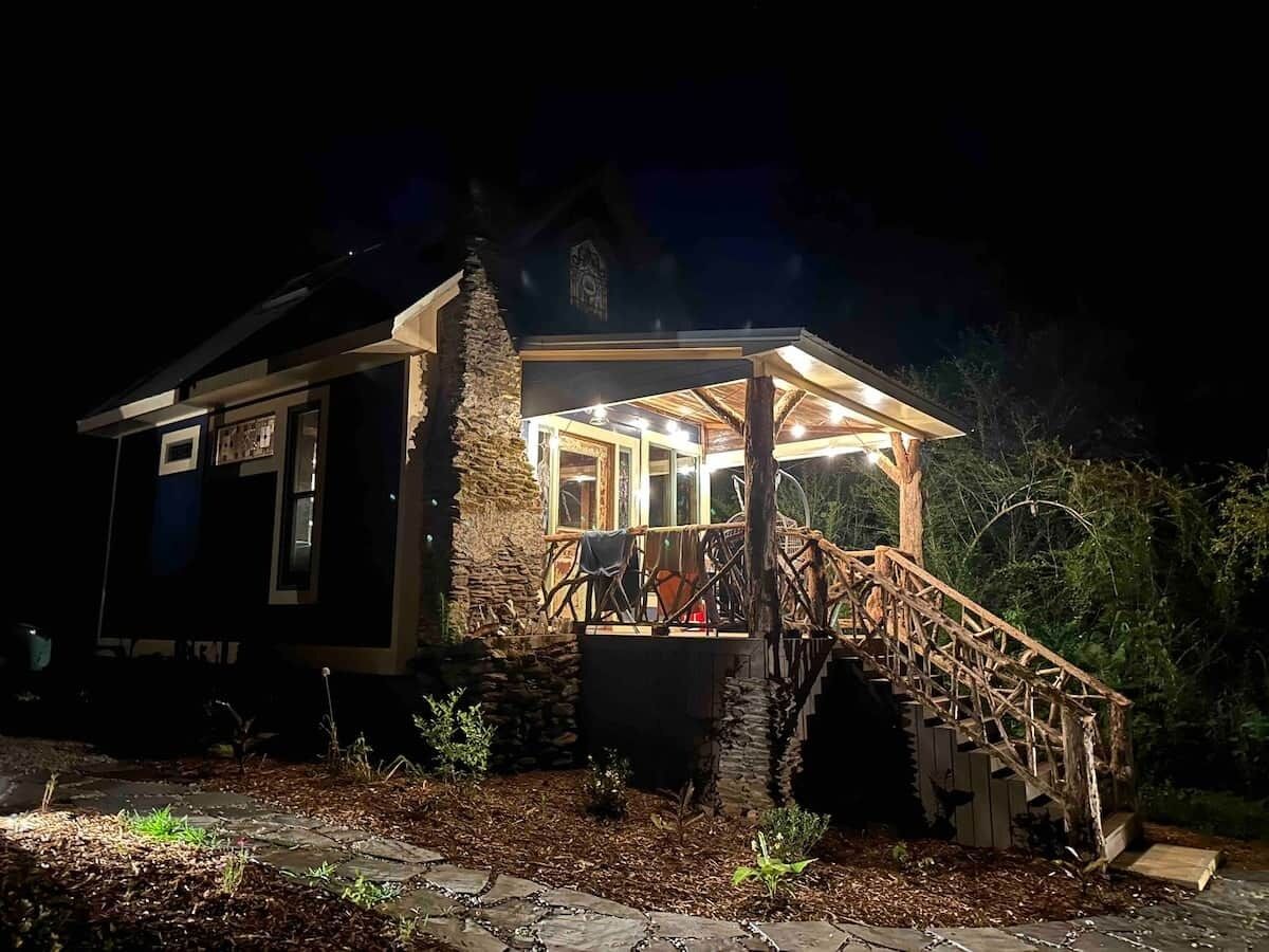 A stone house with a wooden porch and staircase leading to a covered area.