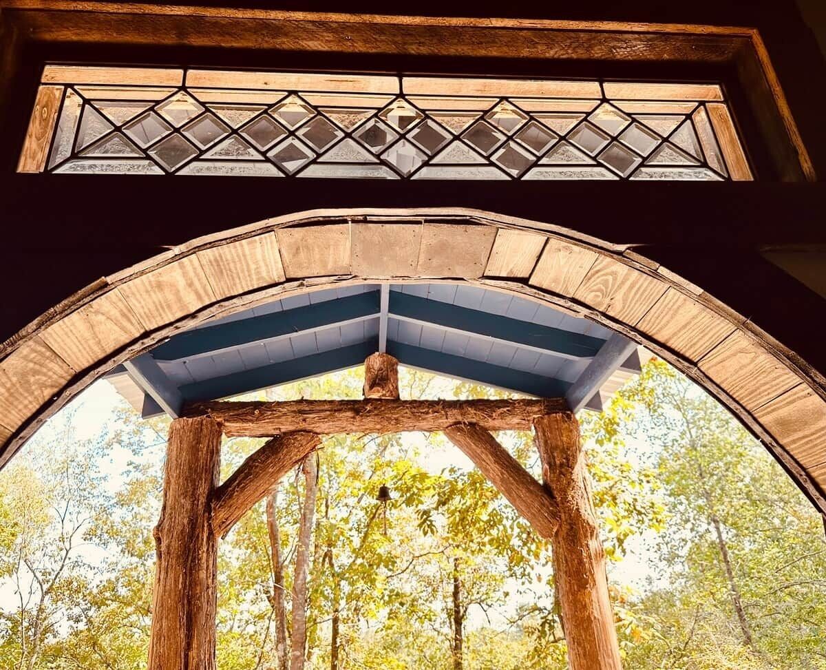 A wooden structure with a triangular roof and a stained glass window above.