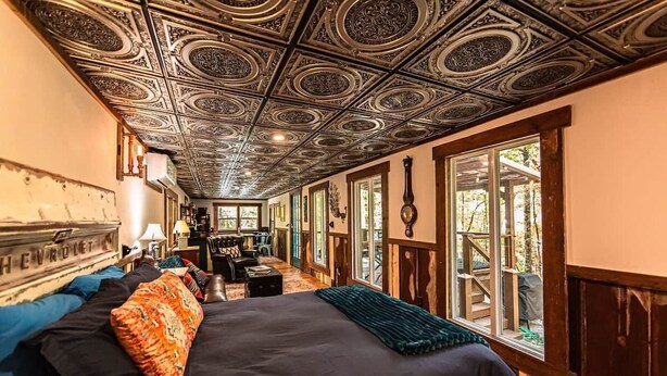 A room with a large bed, a ceiling with intricate patterns, and large windows with a view of the outdoors. - Starry Steampunk on Wolf Creek (Randolph County)
