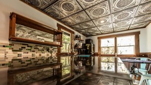 A kitchen with a reflective floor, patterned ceiling, and a window with a view of trees. - Starry Steampunk on Wolf Creek (Randolph County)