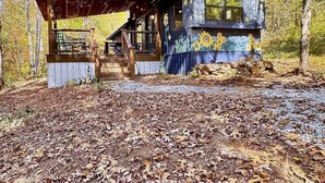 A rustic cabin with a covered porch, a stone foundation, and a wooden deck. - Starry Steampunk on Wolf Creek (Randolph County)
