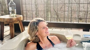 A person relaxing in a hot tub with a glass of wine, a bottle, and a small table with a bottle on it. - Starry Steampunk on Wolf Creek (Randolph County)