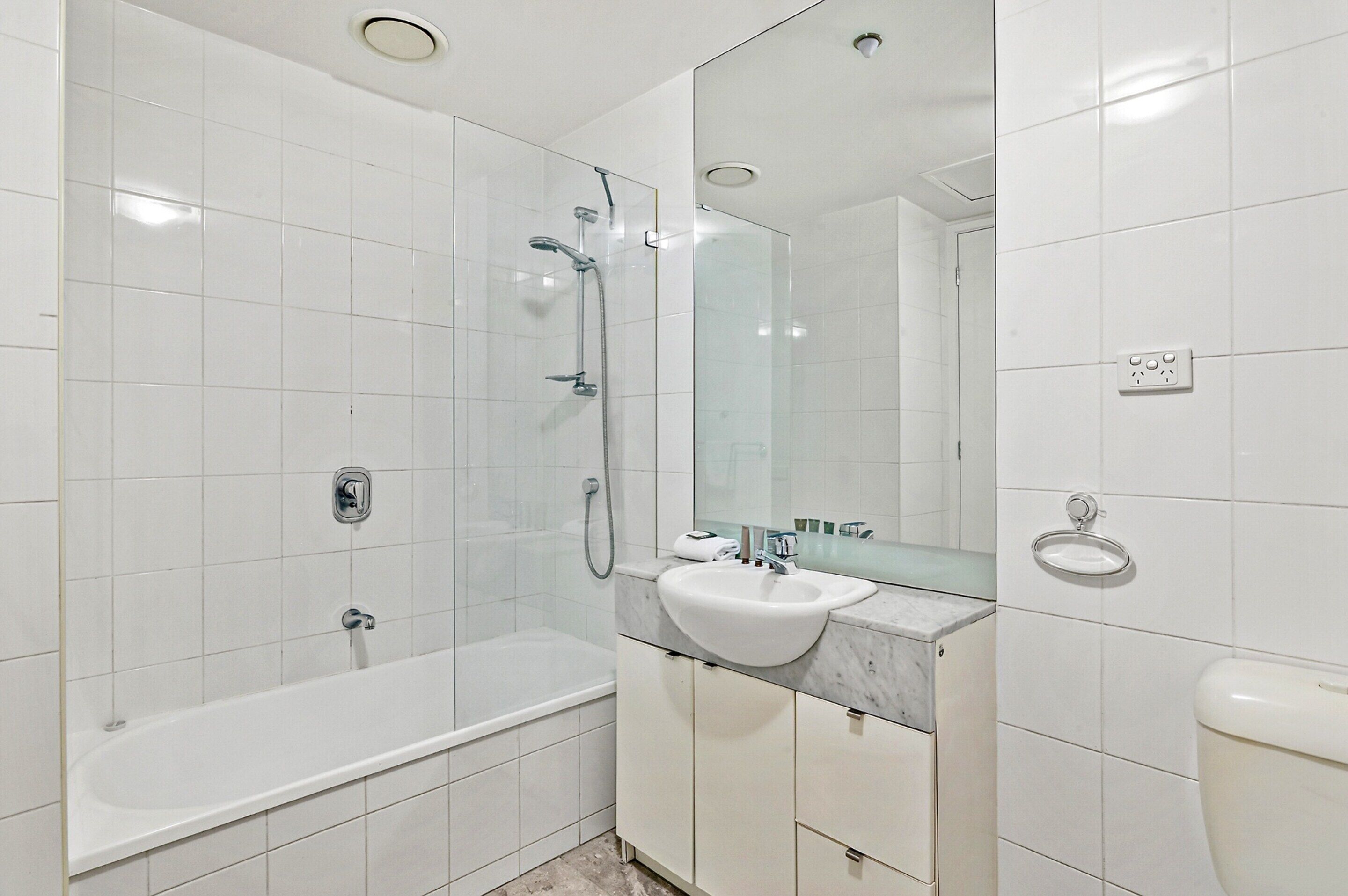 A modern bathroom with a glass-enclosed shower, a standalone bathtub, a white sink, and a large mirror.