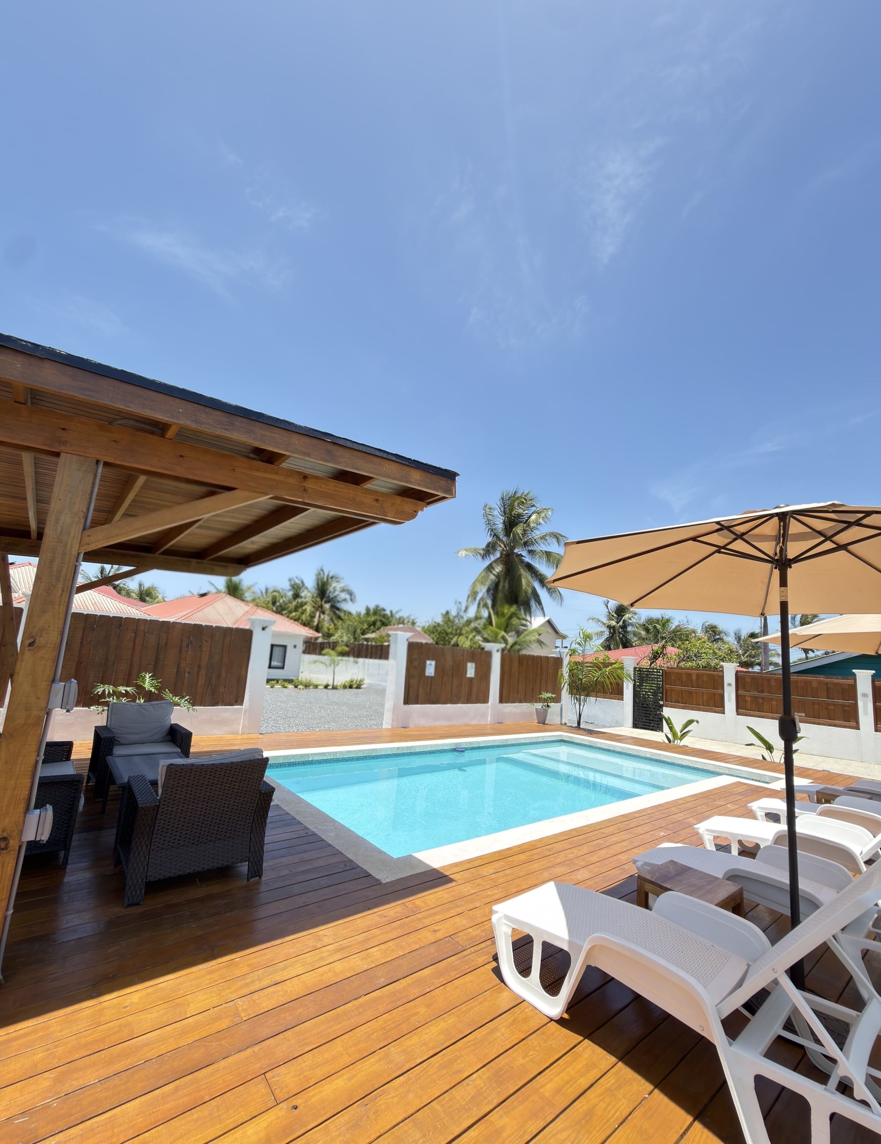 Eine Holzterrasse mit Swimmingpool, Liegestühlen und einer Pergola.