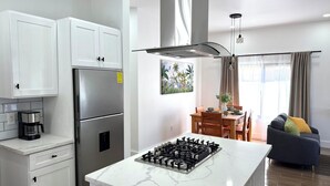 A modern kitchen with a gas stove, stainless steel appliances, and a dining area with a table and chairs.