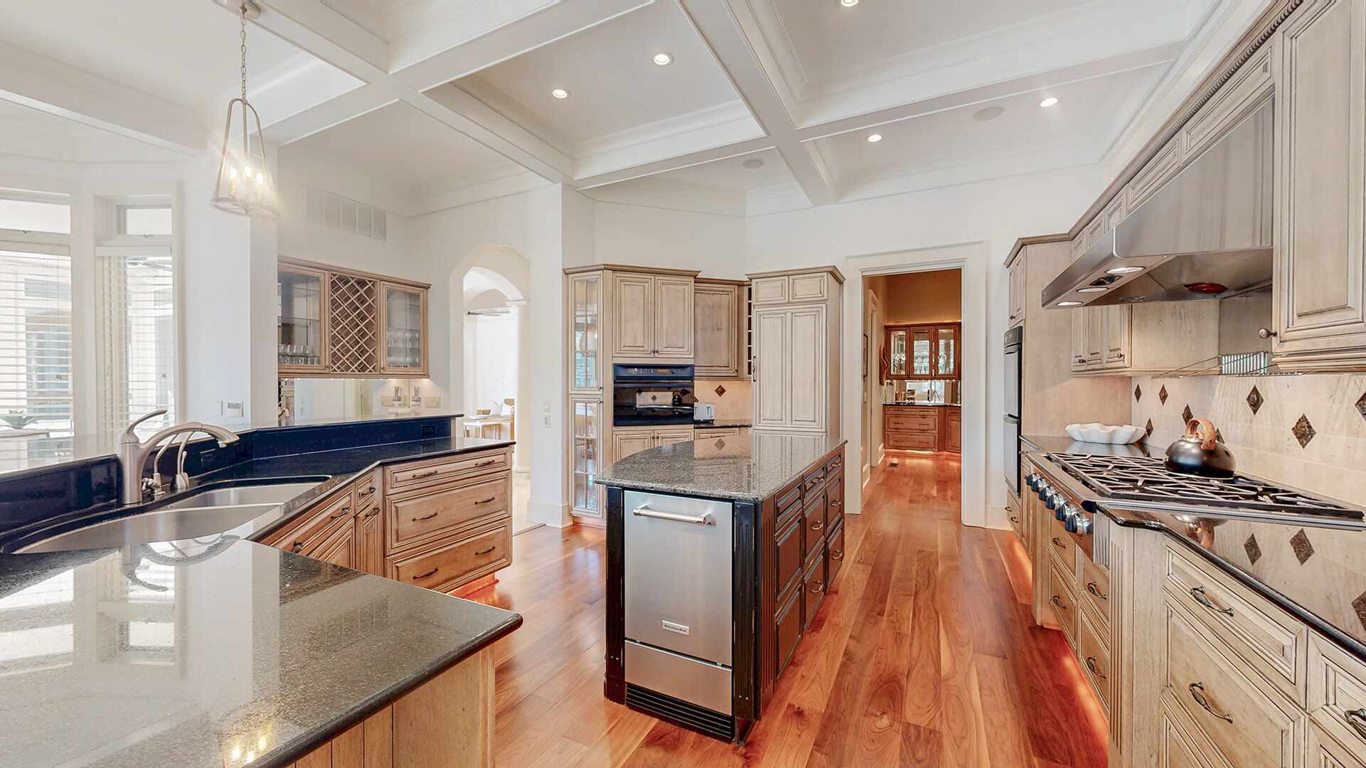 A spacious kitchen with high ceilings, a central island, and built-in cabinetry.