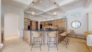 Een ruime keuken met een centraal eiland, barstoelen en een eethoek met een lange bank.