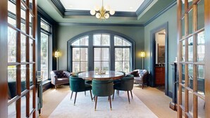 Een kamer met een groot rondboogvenster, een ronde tafel en vier stoelen.
