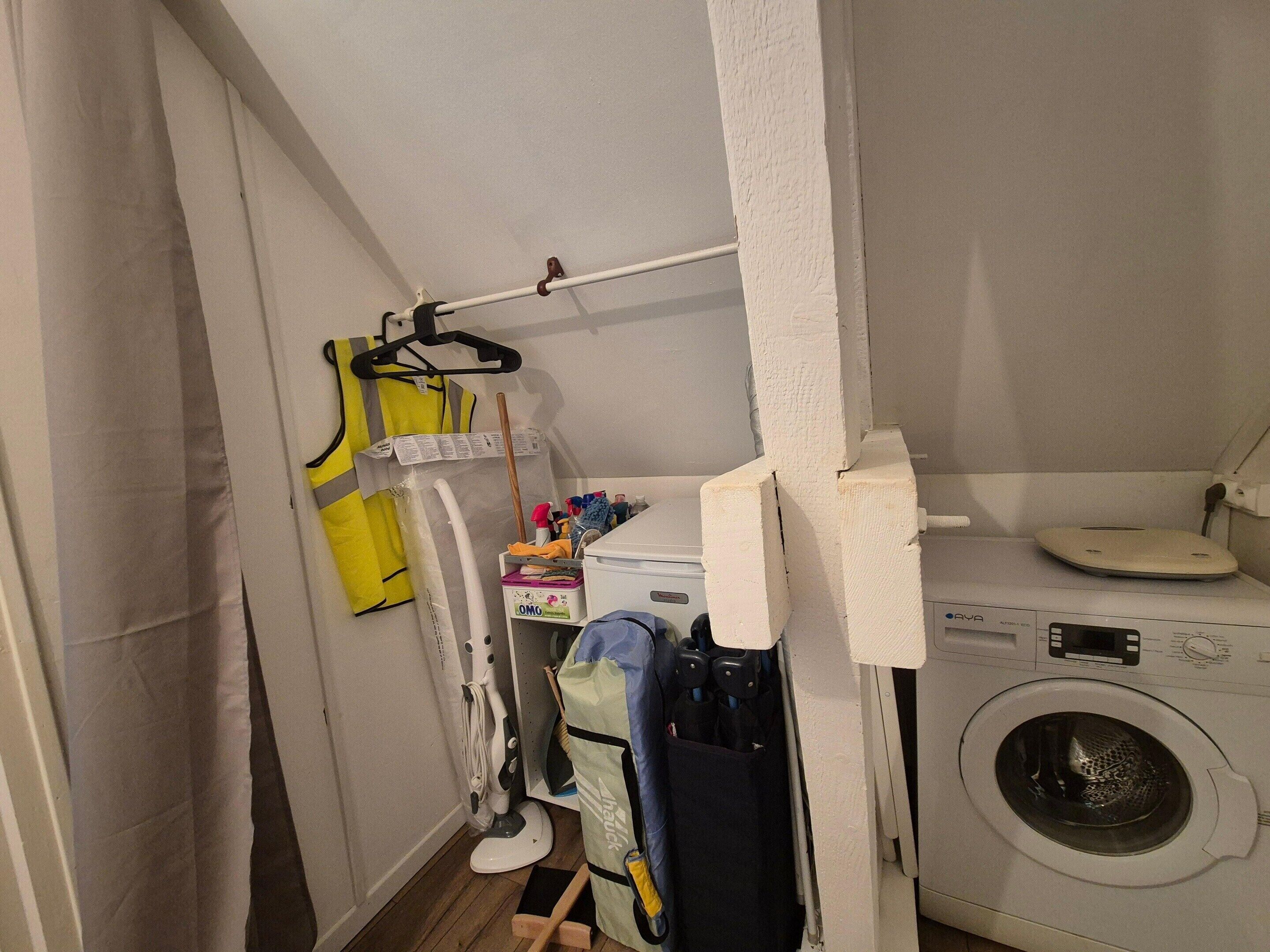 Ein Waschraum mit Waschmaschine, Wäscheständer und Reinigungsmitteln.