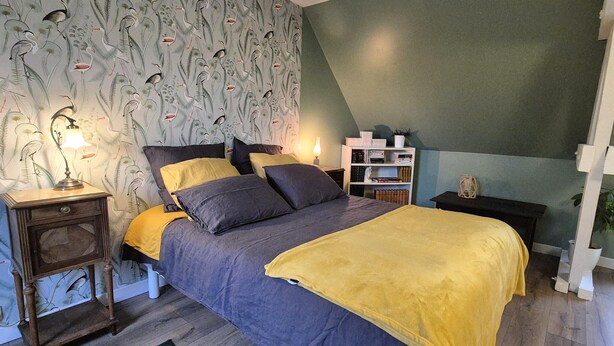 Une chambre à coucher avec un lit, des tables de chevet, une bibliothèque et un papier peint à motifs.