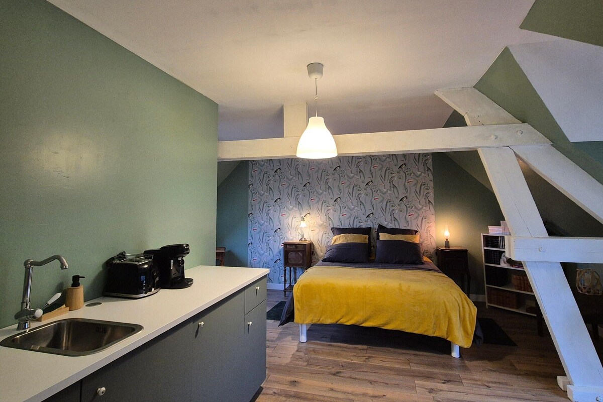 A compact bedroom with a bed, bedside table, and a hanging light fixture.