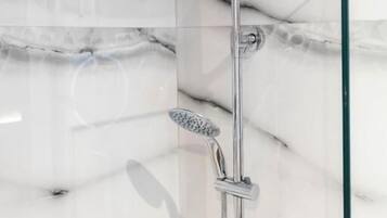 Un baño moderno con cabina de ducha de vidrio, baldosas de mármol y separador de vidrio.
