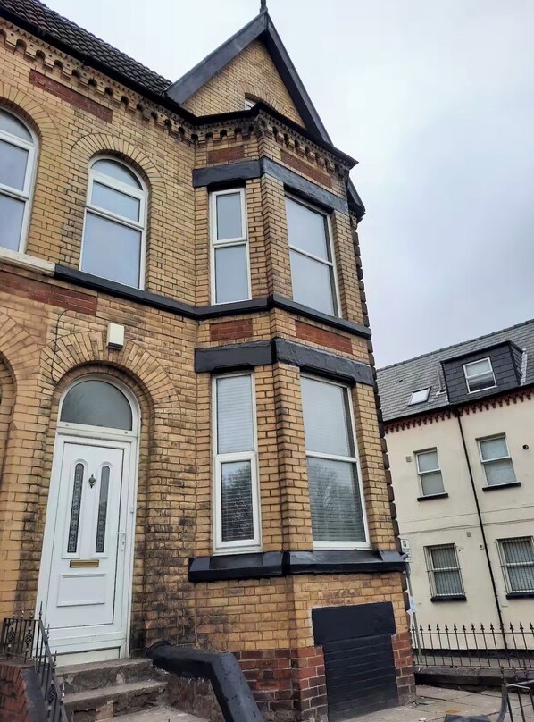 A corner building with a white door, large windows, and a black roof. - 
Authentic designer and artistic house
Family friendly
Close to Anfield and city (Liverpool)