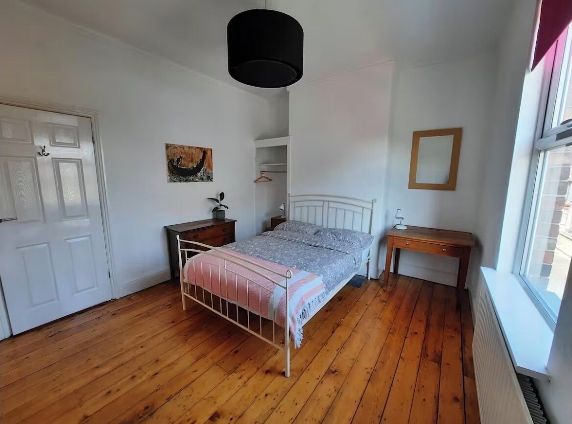 A bedroom with a bed, bedside table, and a window.