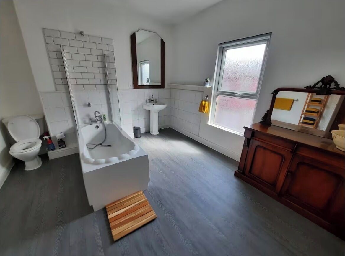 A bathroom with a bathtub, toilet, sink, and wooden vanity.